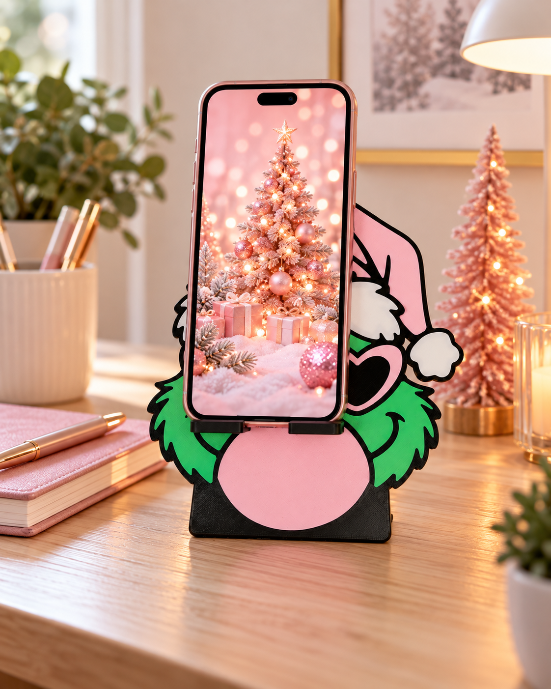Pink and green Grinch-inspired phone holder supporting a phone upright on a desk