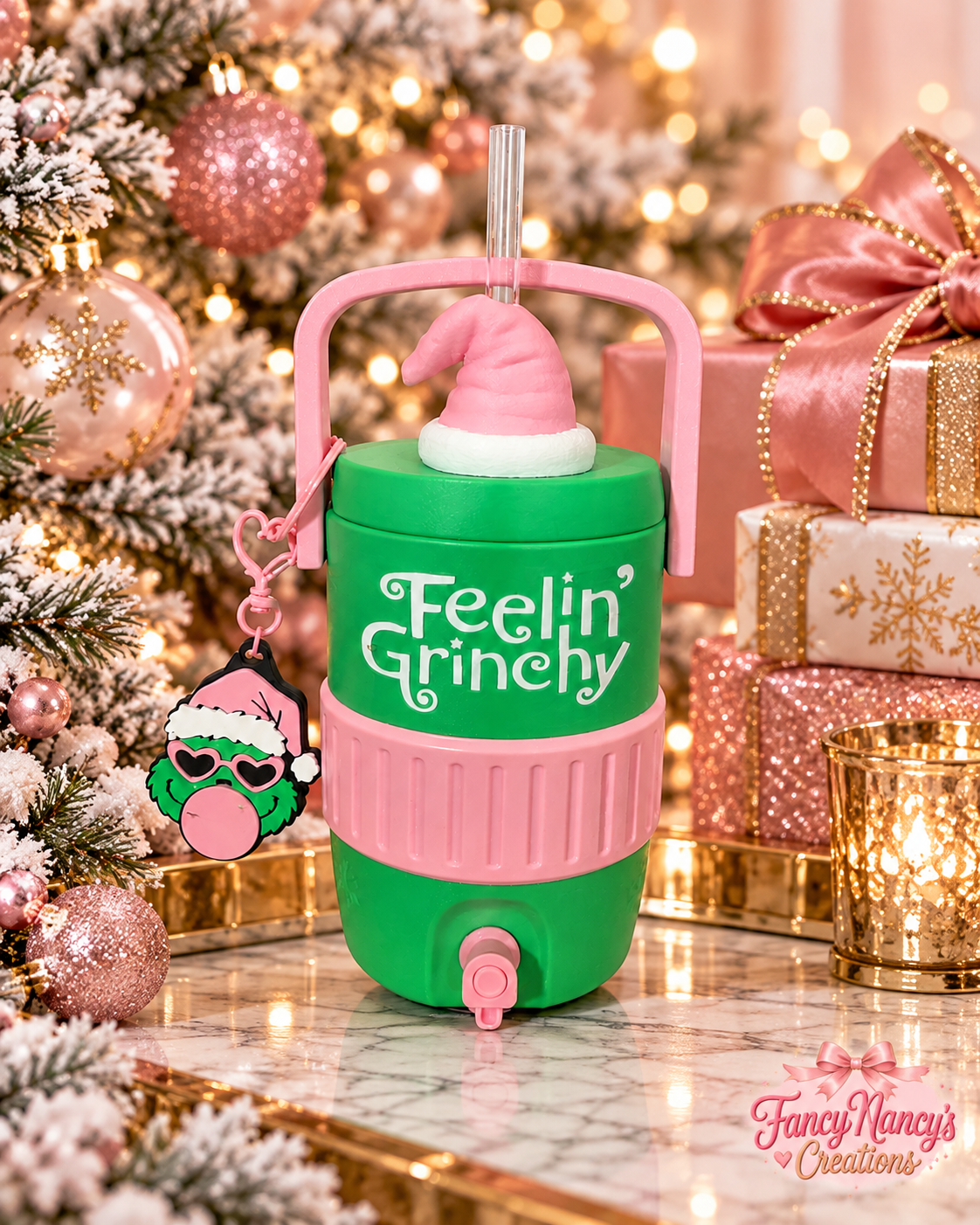 Green Feelin' Grinchy cooler with pink handle, textured pink band and spout, pink Santa hat straw topper and Grinch can tab assist opener keychain.